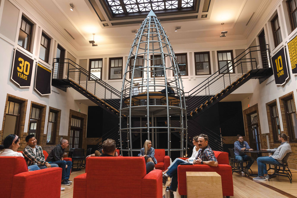 Employees gather in a common area at the Young & Laramore office below Y&L’s rocket sculpture